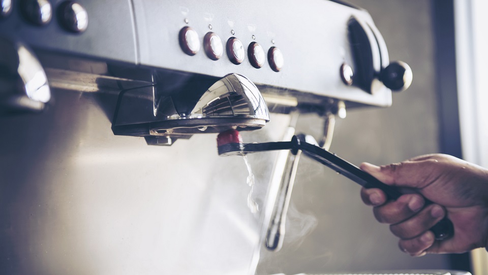 barista cleaning coffee machine at coffee shop